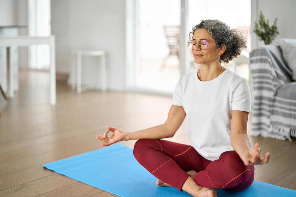 Donna che pratica yoga o meditazione per il benessere durante la menopausa.