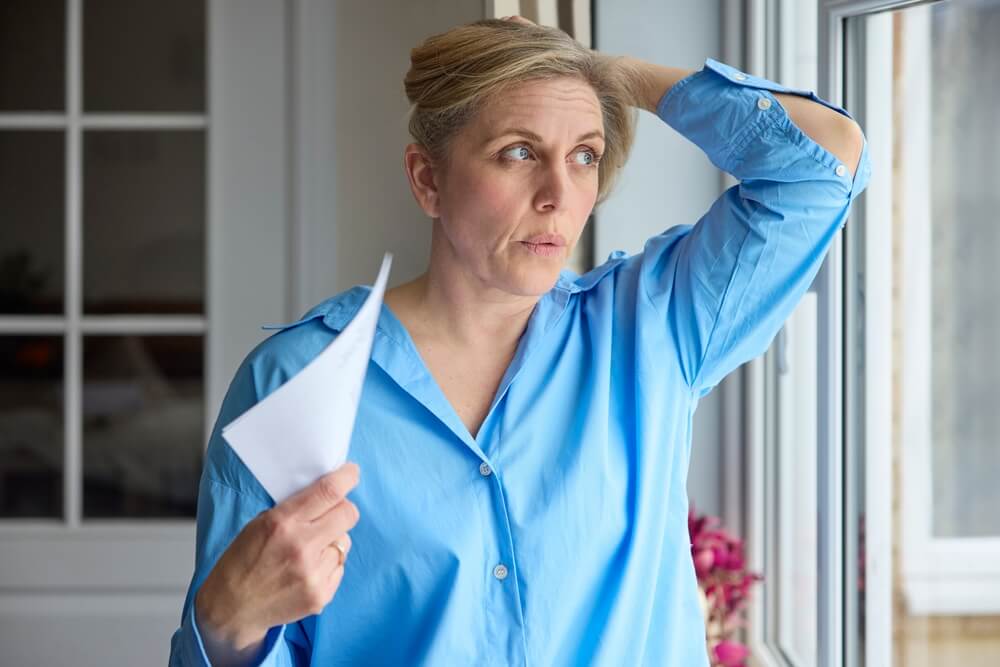 Donna che manifesta sintomi della menopausa, come vampate di calore e stanchezza.